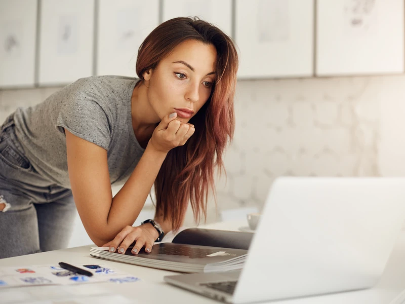 Nữ sinh cúi xem thông tin chương trình trên laptop tại thư viện